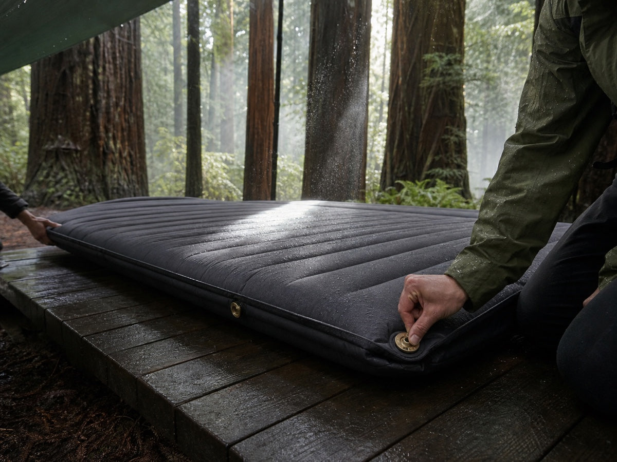 Camper opening the valves on a double self-inflating pad in a redwood forest